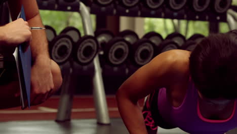 Male-trainer-assisting-woman-with-push-ups