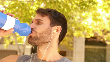 Handsome-young-man-drinking-water-during-jogging-