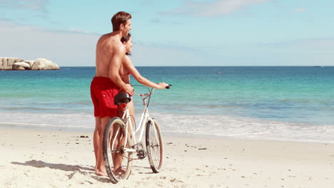 Carefree-couple-going-on-a-bike-ride-on-the-beach