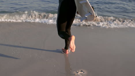 Man-running-into-the-sea-while-holding-a-surfboard