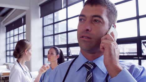 Male-doctor-having-a-phone-call-while-female-doctors-chatting