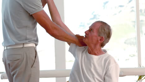 -Old-man-stretching-his-arm-with-trainer