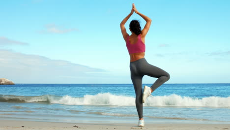 Fitte-Frau-Macht-Yoga-Am-Strand