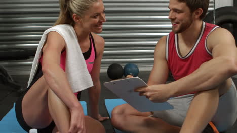 Trainer-talking-with-woman-sitting-on-mat