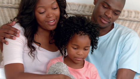 Familia-Feliz-Leyendo-Un-Cuento-En-La-Cama