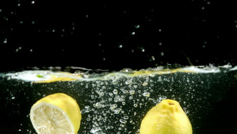 Zitronen-Fallen-Ins-Wasser-Auf-Schwarzem-Hintergrund