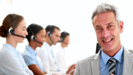 Businessman-looking-at-camera-with-his-colleagues-behind-him-