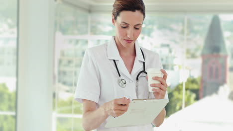 Beautiful-doctor-reading-files-and-looking-at-camera