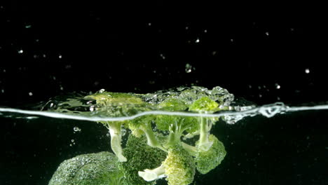Brokkoli-Fällt-Ins-Wasser-Auf-Schwarzem-Hintergrund