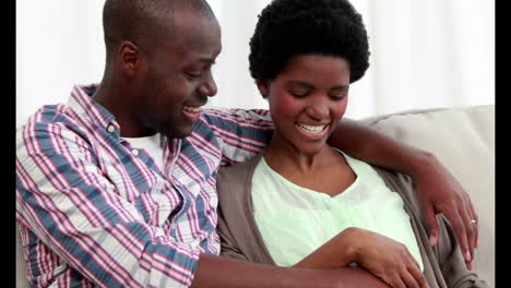 Pregnant-woman-with-her-husband-sitting-on-the-couch