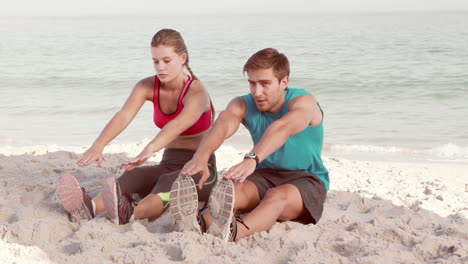 Smiling-couple-stretching-their-legs-on-the-beach