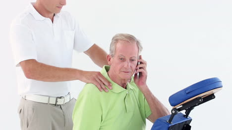 Doctor-massaging-his-patients-shoulders-while-he-calling-