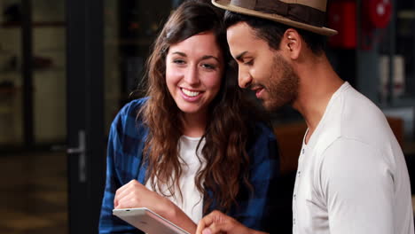 Smiling-couple-looking-at-tablet-