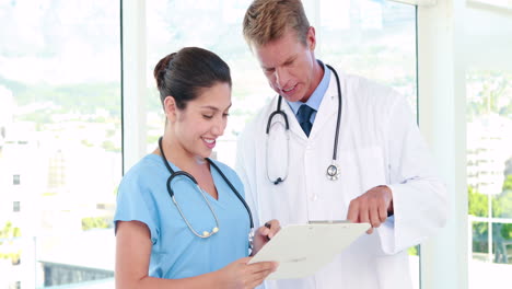 Doctor-looking-at-clipboard-with-nurse