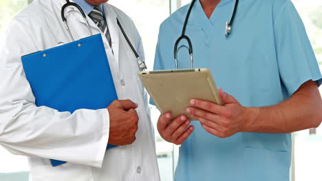 Two-doctors-holding-clipboard-in-medical-office