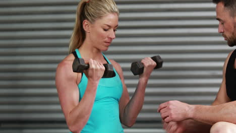 Trainer-explaining-to-woman-how-to-use-dumbbells
