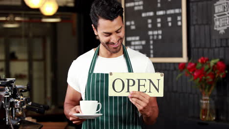 Smiling-waiter-holding-sign-and-coffees-cup