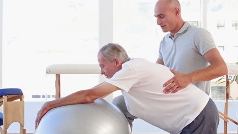 Doctor-helping-his-patient-to-stretch-with-exercise-ball