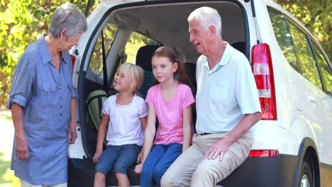 Glückliche-Familie-Sitzt-Auf-Dem-Kofferraum-Eines-Autos