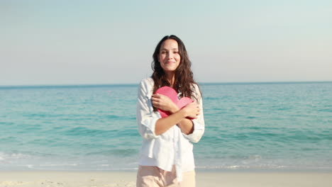 Lächelnde-Frau-Mit-Herzkarte-Am-Strand