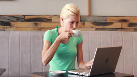 Hübsche-Blondine-Mit-Ihrem-Laptop-Und-Trinkt-Kaffee-