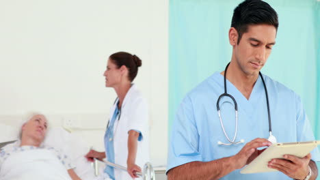 Doctor-looking-using-tablet-computer-while-his-colleagues-speaking-with-patient-