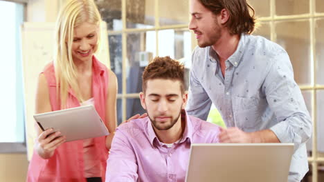 Smiling-casual-businesswoman-showing-tablet-to-colleagues