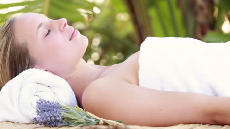 Woman-lying-on-massage-table-at-tropical-spa