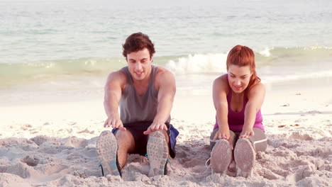Smiling-couple-stretching-their-legs-on-the-beach