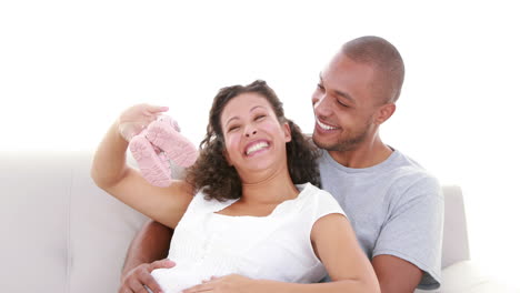 Schwangere-Frau-Zeigt-Babyschuhe-Auf-Dem-Sofa