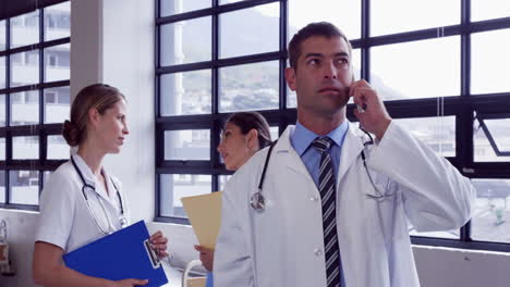 Male-doctor-having-a-phone-call-while-female-doctors-chatting