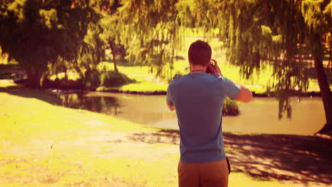 Rear-view-of-man-walking-and-taking-photo-with-retro-camera