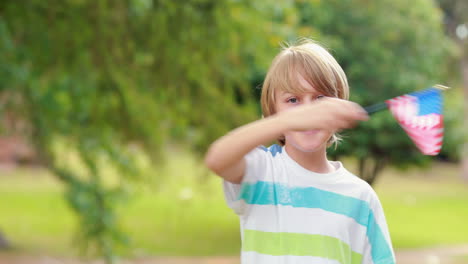 Little-boy-smiling-at-camera-and-waving-american-flag