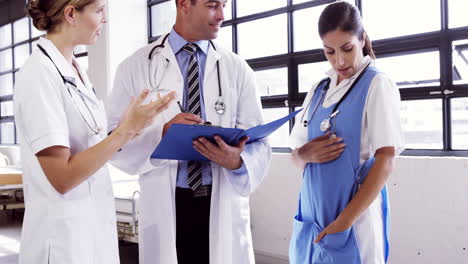 Doctors-speaking-together-while-writing-notes-on-clipboard