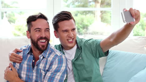 Gay-couple-relaxing-on-the-couch-taking-selfie