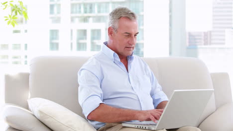 Smiling-businessman-working-on-his-laptop