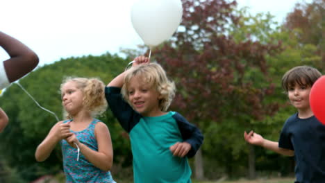 Niños-Felices-Jugando-Con-Globos-En-El-Parque