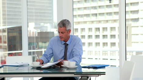 Serious-businessman-writing-on-notebook