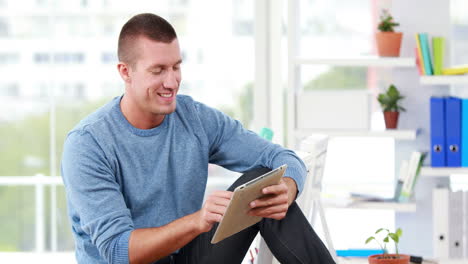Smiling-casual-businessman-using-his-tablet