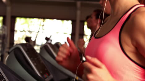 Fit-woman-running-on-treadmills-while-listening-music