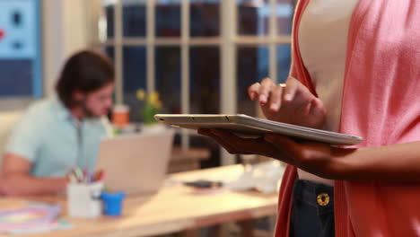 Casual-businesswoman-using-tablet-in-front-of-colleague