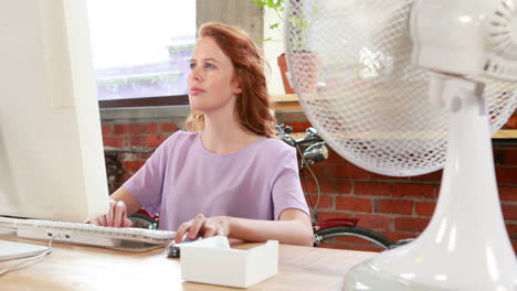 Casual-businesswoman-working-at-her-desk