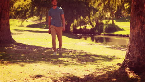 Un-Hombre-Guapo-Caminando-Por-El-Parque-Y-Sosteniendo-Una-Cámara-De-Fotos-Retro.