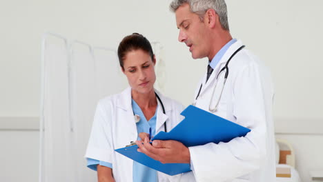 Two-doctors-looking-at-clipboard-in-medical-office