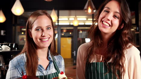 Smiling-waitresses-showing-cakes