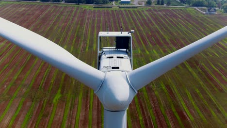 Windturbine-Mit-Aufsteigender-Drohne-über-Rotorkonus-Und-Propeller-Zur-Nahinspektion-Vor-Ackerland-Hintergrund