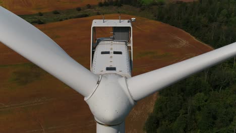 Wind-Turbine-Nacelle-with-Propeller-Blades-Close-Up-Aerial-Tilt-Down-Dolly-Shot-Over-Farmland