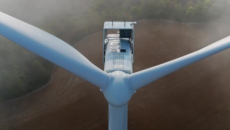 Windturbine-Mit-Nebel-Im-Hintergrund,-Nahaufnahme-Einer-Drohne-Aus-Der-Luft-Von-Propellern-Zur-Inspektion