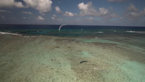 A-kitesurfer-glides-across-the-crystal-clear-blue-waters-of-Los-Roques-under-a-bright-sky