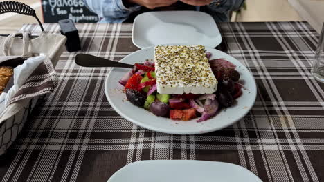 Mujer-Con-Su-Teléfono-En-La-Mano-Tomando-Una-Fotografía-De-Una-Ensalada-Griega-Con-Queso-Feta-En-Una-Taberna.